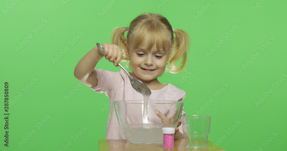 Child having fun making slime. Mixes ingredients. Kid with hand made toy Child having fun making slime. Mixes ingredients. Kid with hand made toy