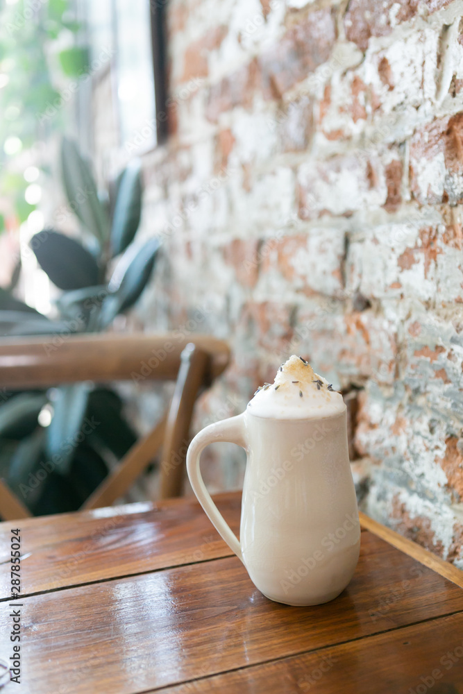 Obraz premium Lavender london fog tea latte with steamed milk and sugar on table in cafe, brick background, copy space