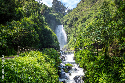 View of Peguche Waterfall in the mountains of Ecuador. It's surrounded by green forest full of vegetation