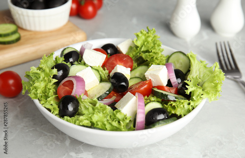 Tasty fresh Greek salad on grey marble table, closeup