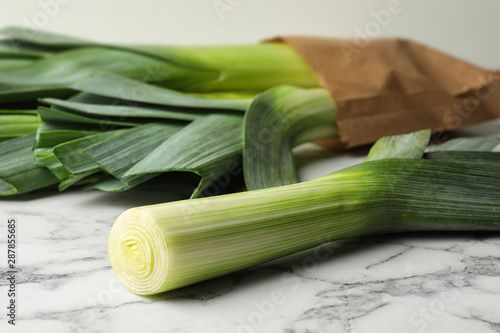 Fresh raw leeks on marble table  closeup. Ripe onion