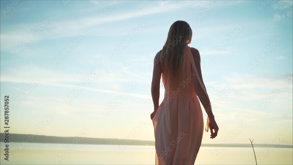 girl in a wet dress in the water against the background of dawn.. Silhouette of a girl at sunset against the background of a vintage ship