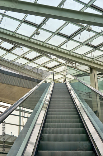 Escalator under a large glass roof.