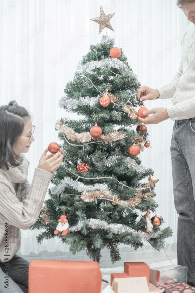 Merry christmas happy couple people decorate the christmas tree for happy holidays in home, christmas concept Merry christmas happy couple people decorate the christmas tree for happy holidays in home, christmas concept