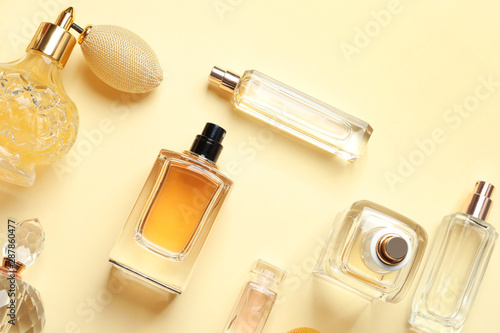Flat lay composition with different perfume bottles on light yellow background