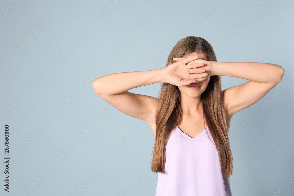 Young woman being blinded on grey background, space for text Young woman being blinded on grey background, space for text