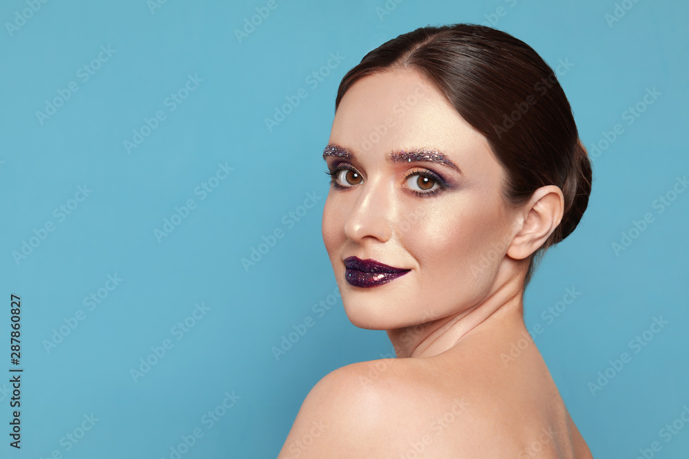 Beautiful young woman with glitter makeup on blue background, space for text Beautiful young woman with glitter makeup on blue background, space for text