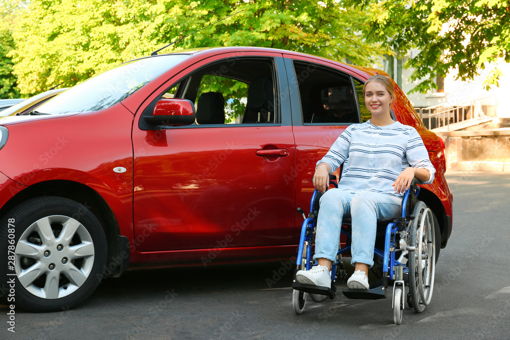 Young woman in wheelchair near car outdoors