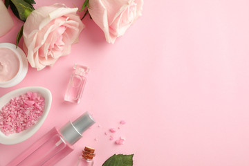 Flat lay composition with rose essential oil on pink background, space for text