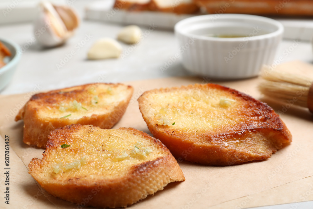 Slices of delicious toasted bread with garlic on table, closeup Slices of delicious toasted bread with garlic on table, closeup