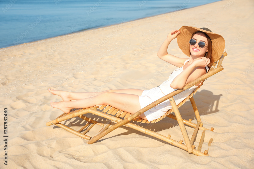 Young woman relaxing in deck chair on sandy beach Young woman relaxing in deck chair on sandy beach