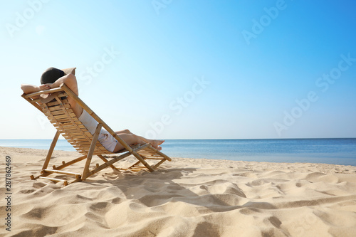 Valokuva Young woman relaxing in deck chair on sandy beach