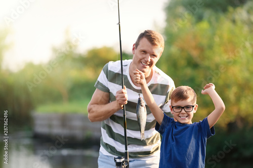 Dad and son fishing together on sunny day