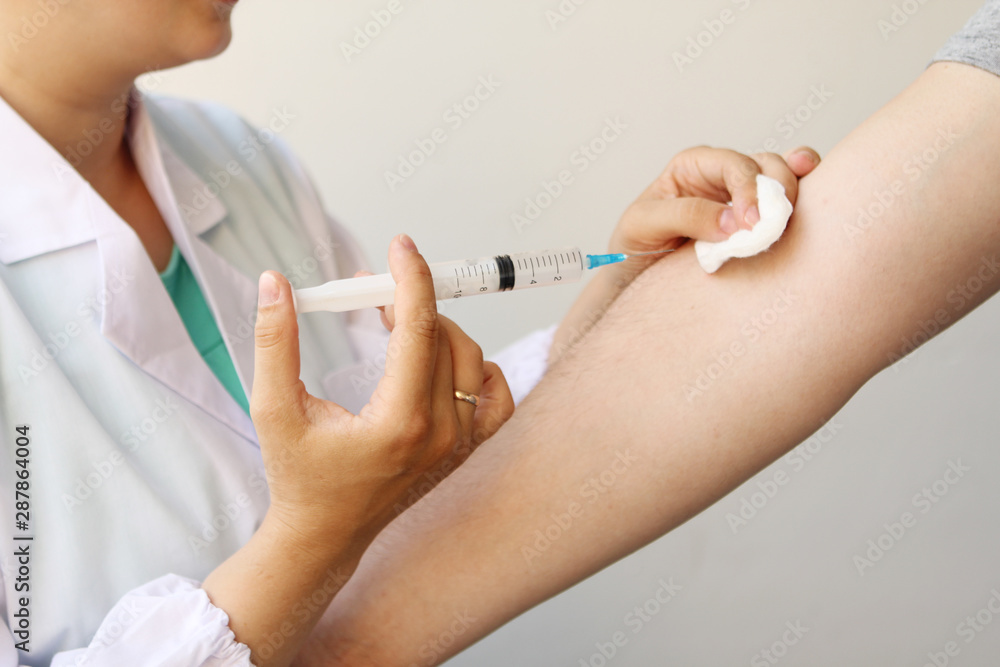 female doctor, nurse in white uniform makes an injection with a syringe in a man’s hand, medical concept, close-up, copy space female doctor, nurse in white uniform makes an injection with a syringe in a man’s hand, medical concept, close-up, copy space