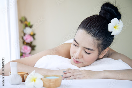 Close up of attractive young Asian woman laying and closing eyes during getting Spa treatment on white bed