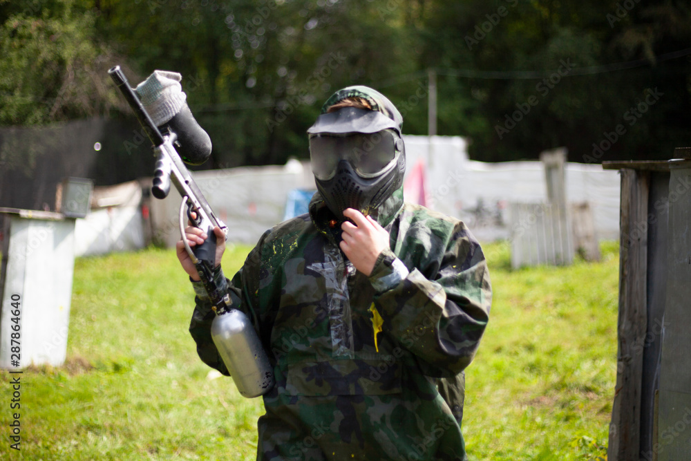 Fototapeta premium Paintball game. Soldiers compete in paint marker firing. Tactical battle. Player on the training ground.