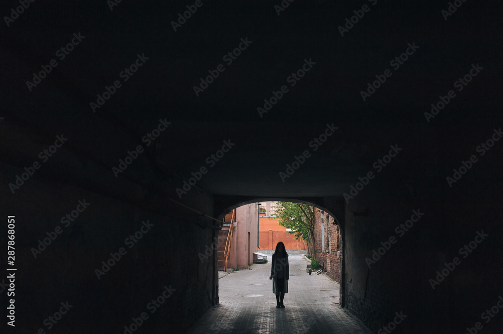 Silhouette of a young european girl in an old arch. The concept of loneliness, tourism, slums and poverty.