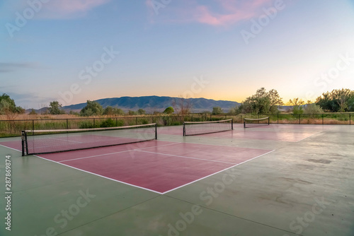 Tennis courts with an amazing view of mountain blue sky and glowing sunset © Jason