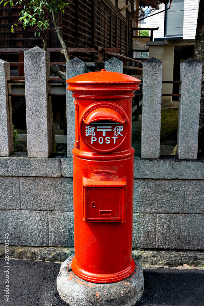 Old fashioned red postbox on street. Translation; Two Japanese characters on the post mean Old fashioned red postbox on street. Translation; Two Japanese characters on the post mean