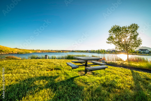 Picnic table at a park with scenic view of a lake that reflects the sky and sun