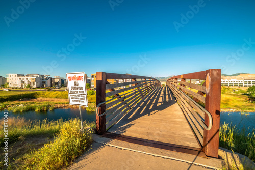 Bridge over a lake with view of buildings mountain and blue sky on a sunny day © Jason