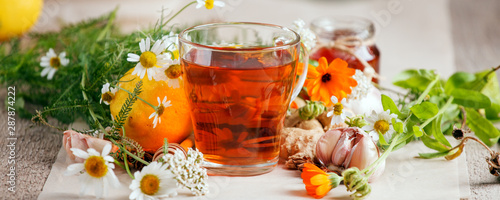 Photography Cup of herbal tea with wild flowers and various herbs, garlic, ginger root