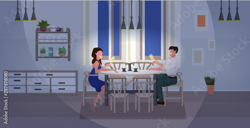 romantic couple having candlelight dinner man woman sitting at table drinking champagne modern home kitchen interior flat horizontal full length