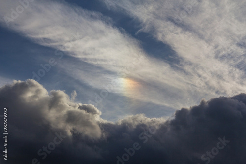 Rainbow colored sundog in cloudy blue sky