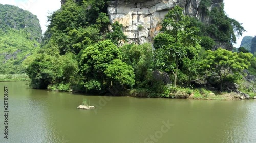 aerial flying drone above a river on the way to a limestone mountain throught the trees. Tam Coc, Unesco world heritage in north Vietnam photo