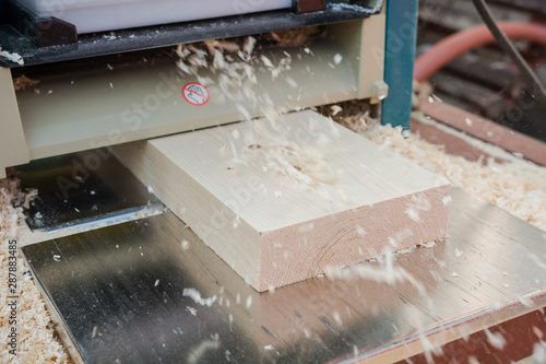 planing boards on a thicknesser. wood shavings. machine for planing wood. carpentry work. joiner's machine.