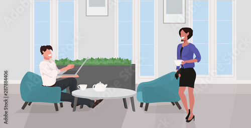 man woman drinking tea relaxing at home couple having fun using laptop and discussing together modern living room interior flat full length horizontal