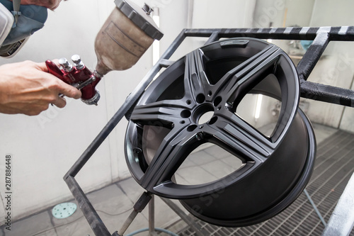 Papier peint Painting the element body of the car - the aluminum alloy wheel with the help of aerograf in black color by the hand of painter repairman in the industrial professional garage