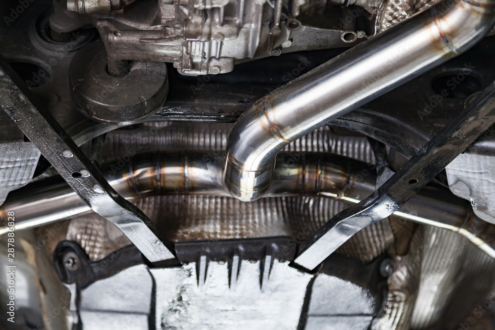 Fabrication and installation of a stainless steel car exhaust pipe with a bifurcation and a louder sound with a color weld under bottom. Tuning and auto service industry. Fabrication and installation of a stainless steel car exhaust pipe with a bifurcation and a louder sound with a color weld under bottom. Tuning and auto service industry.