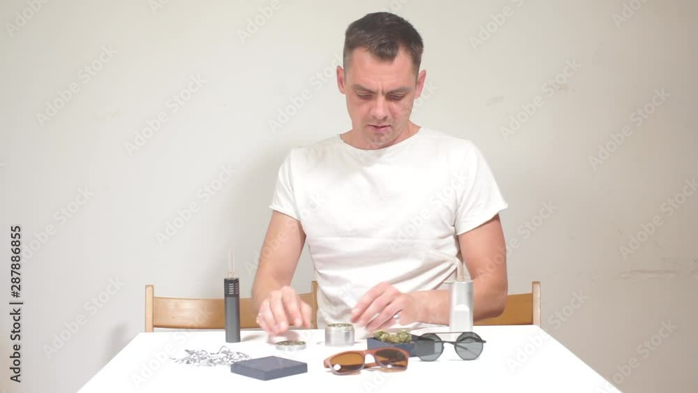 guy puts cannabis in the grinder to make a joint guy puts cannabis in the grinder to make a joint
