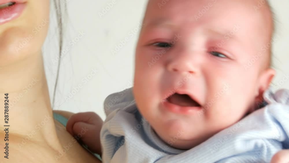 A two month old newborn baby cries loudly. Childs face close up view A two month old newborn baby cries loudly. Childs face close up view