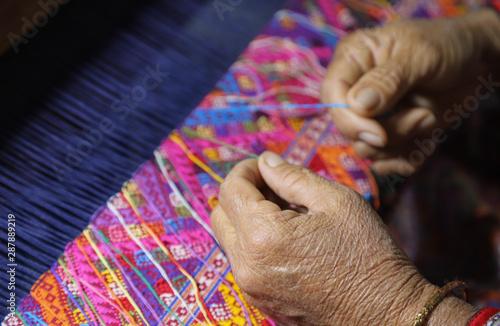 Closeup of skillful elderly woman's hands doing cloth weaving.