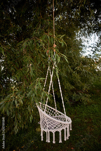 Swing knitted macrame hanging out in nature. Hammock for relaxation. Boho style photo