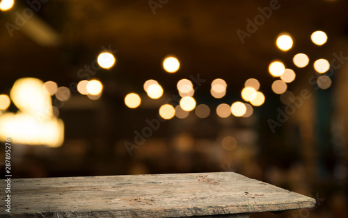 Empty wood table top on blur light gold bokeh of cafe restaurant in dark background