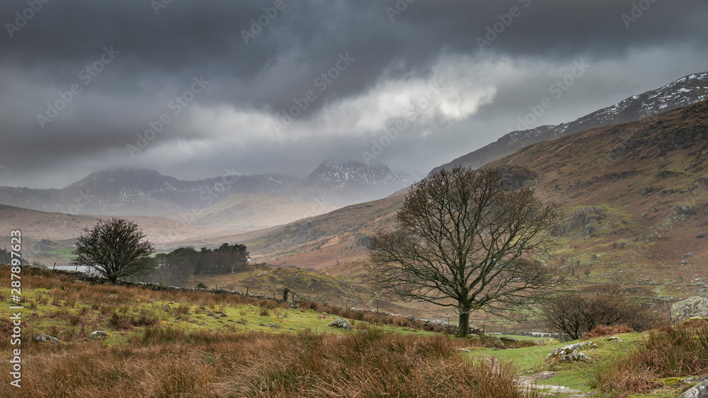 Beautiful Winter landscape image looking along valley from Crimpiau towards Mount Snowdon in the distance