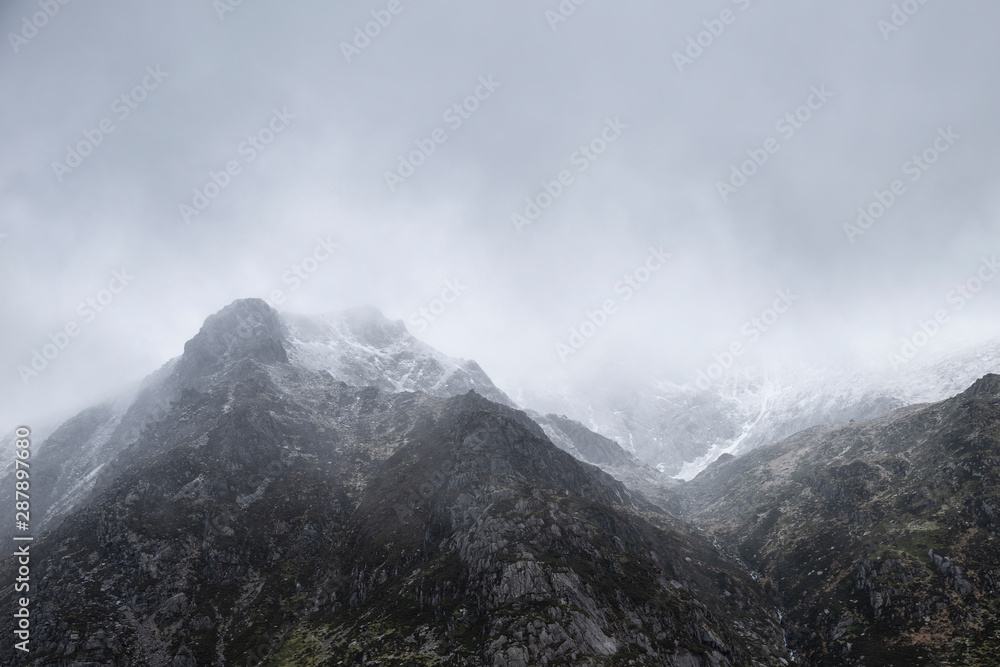 Stunning moody dramatic Winter landscape image of snowcapped Y Garn mountain in Snowdonia