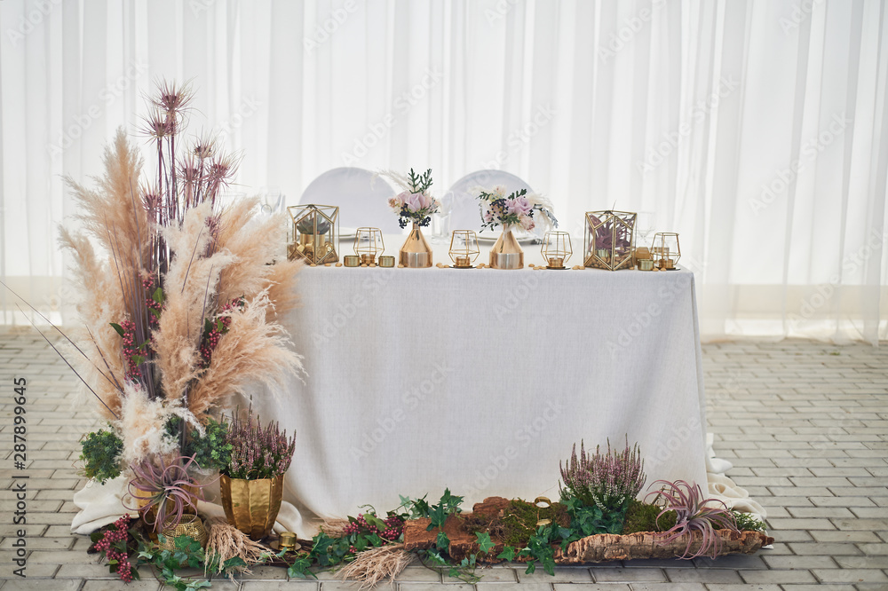 Wedding decoration in boho style. Light colors, in the tent.Wedding table  decorated with pampas grass. Roses and gold geometric candlesticks. Stock  Photo | Adobe Stock