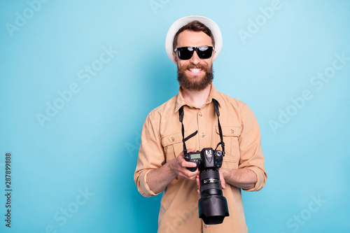 Portrait of charming guy holding camera wearing brown shirt eyeglasses eyewear isolated over blue background photo