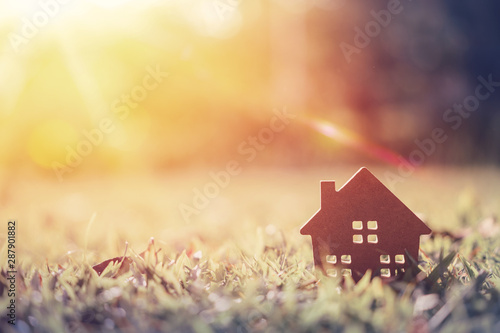 Copy space of home and life concept. Small model home on green grass with sunlight abstract background.