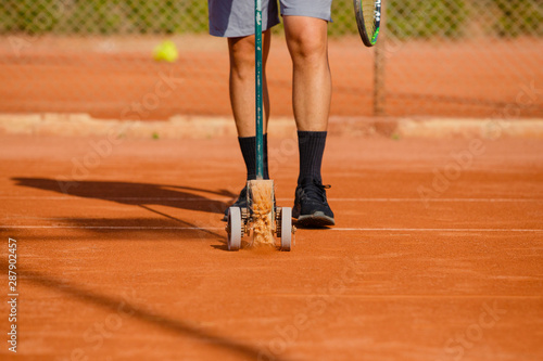 unrecognizable man with sweeps lines of tennis court © Miguel Valls