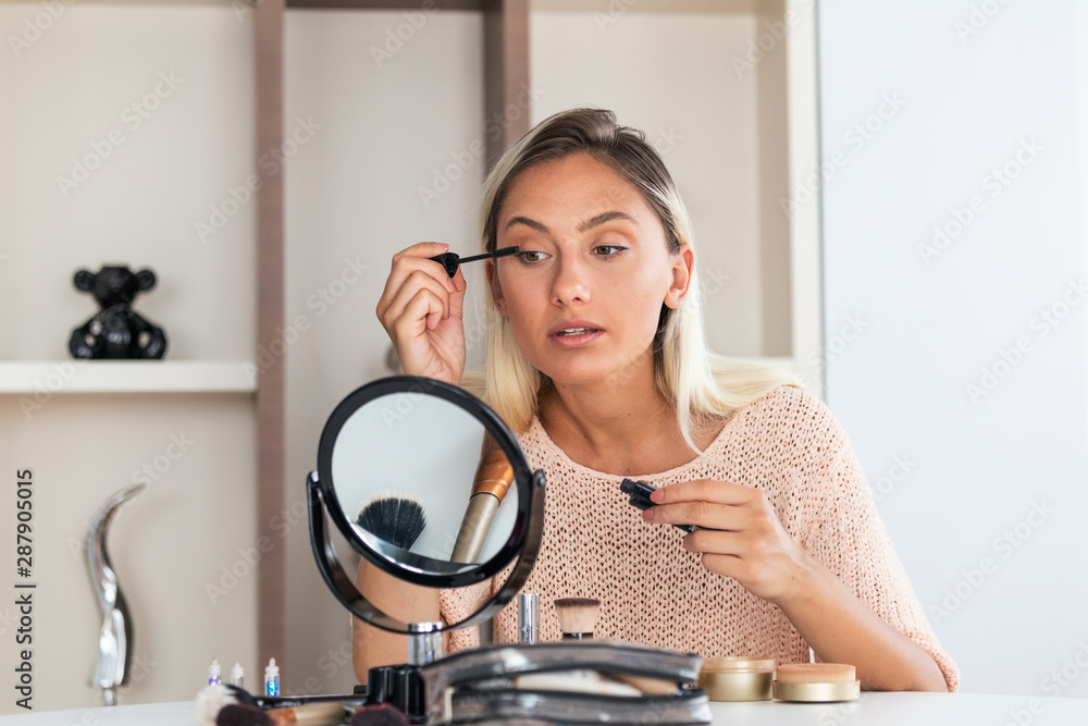 Woman Applying Black Mascara on Eyelashes with Makeup Brush. Beauty Make-up. Portrait Of Beautiful Young Woman Applying Black Mascara On Lashes, Holding Brush In Hand. Woman Applying Black Mascara on Eyelashes with Makeup Brush. Beauty Make-up. Portrait Of Beautiful Young Woman Applying Black Mascara On Lashes, Holding Brush In Hand.