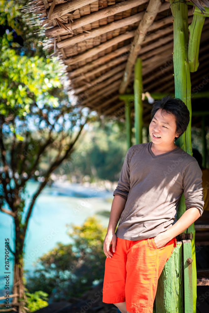 Fototapeta premium Asian Thai Chinese man smile and relax in this vacation day at the weekend in nature environment in green vintage pavilion