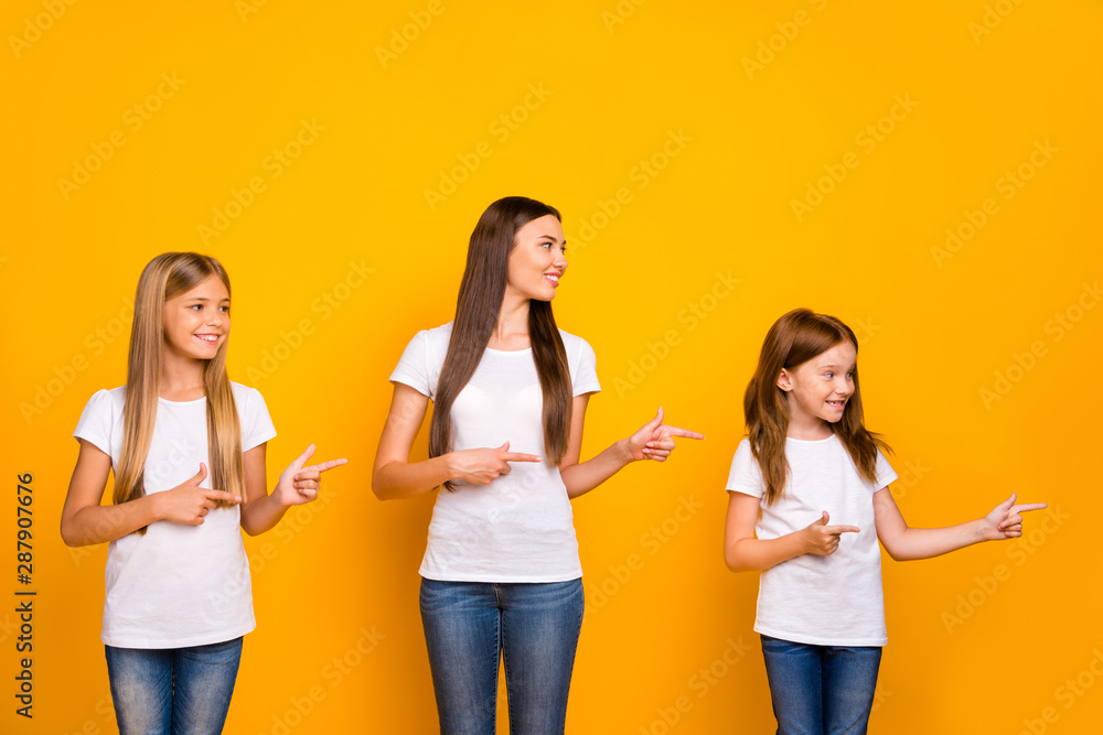 Fototapeta premium Photo of charming ladies indicating fingers side empty space wear casual clothes isolated yellow background