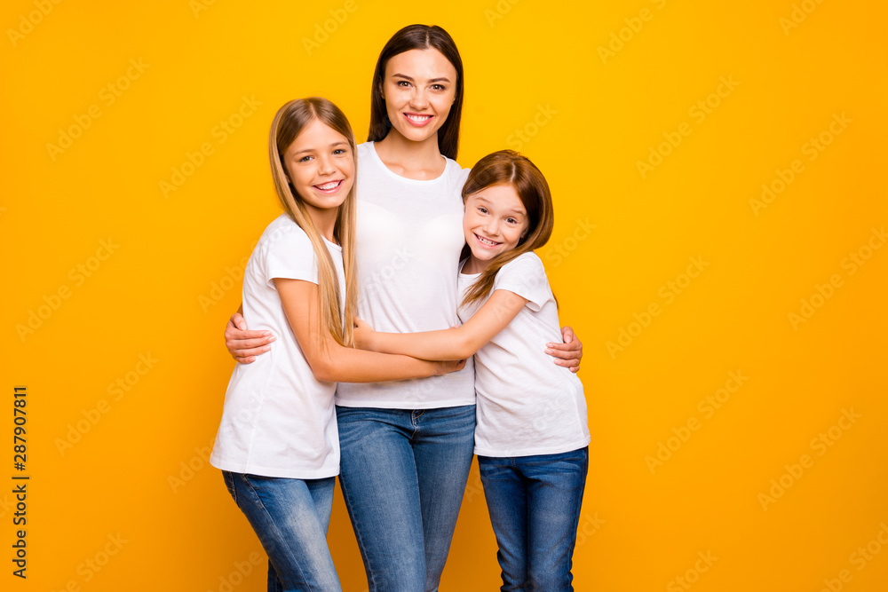 Two small ladies hugging young and beautiful babysitter wear casual white t-shirts isolated yellow background Two small ladies hugging young and beautiful babysitter wear casual white t-shirts isolated yellow background