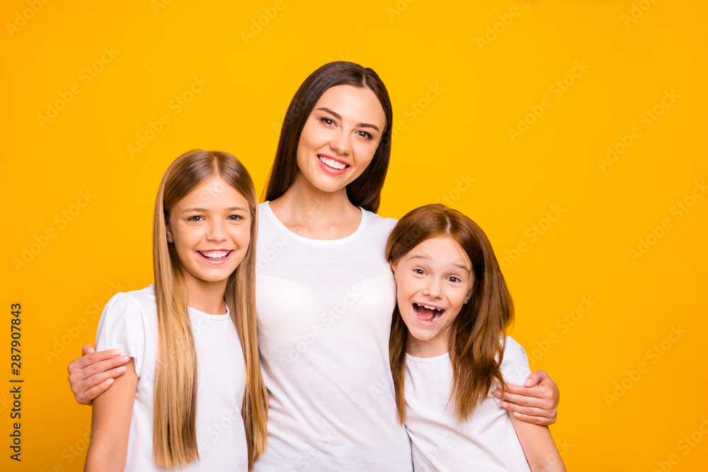 Two small ladies with young nanny hugging wear casual white t-shirts isolated yellow background Two small ladies with young nanny hugging wear casual white t-shirts isolated yellow background