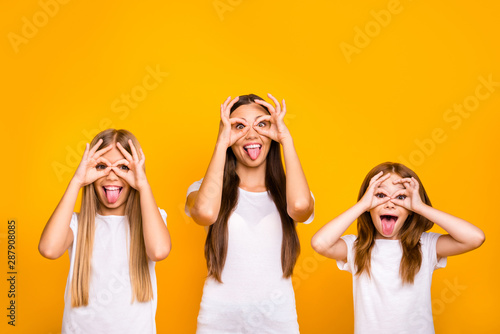 Three sister ladies holding okey symbols near eyes like specs fooling around wear casual outfit isolated yellow background